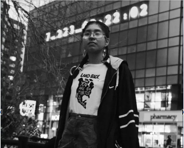 Black and white photo of a person outside and wearing glasses. 
