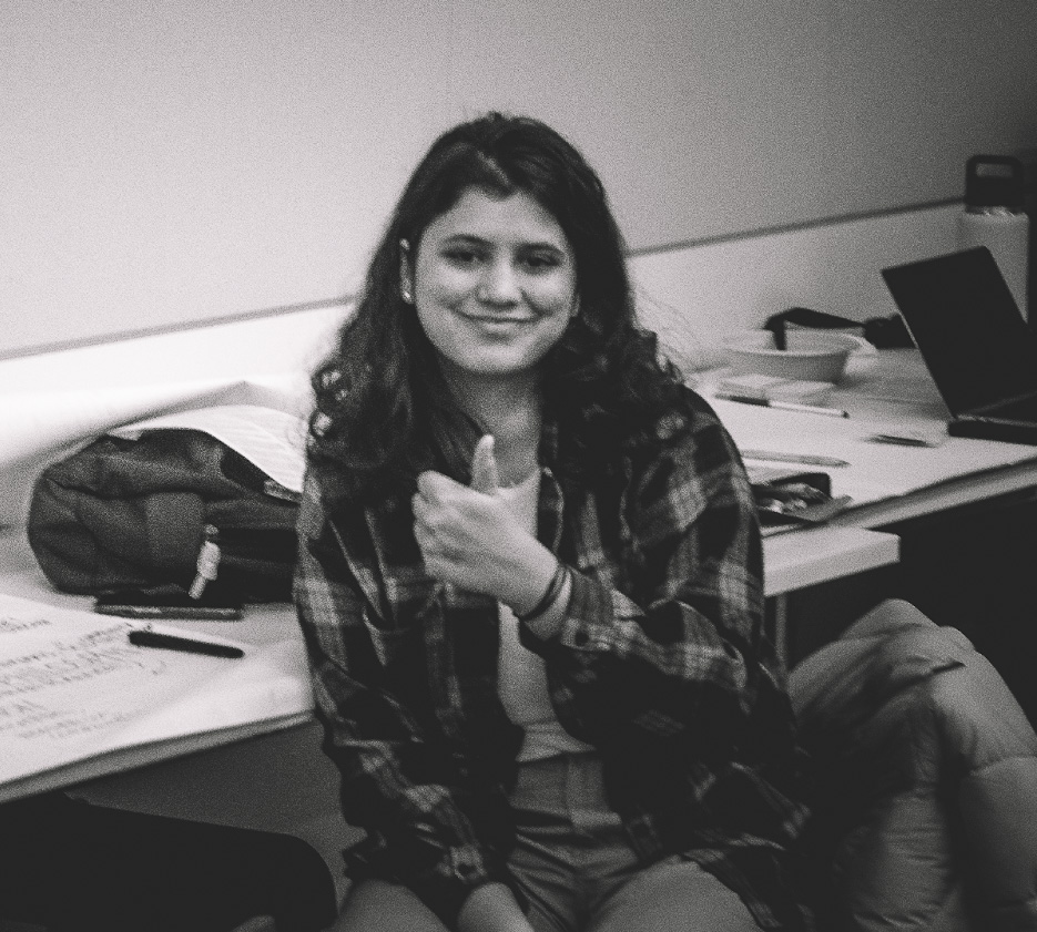 black and white photo of a person smiling and doing a "thumbs up" gesture. 