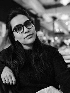 Person wearing dark top and black glasses