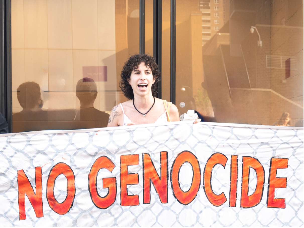 person with curly brown hair holding sign. 