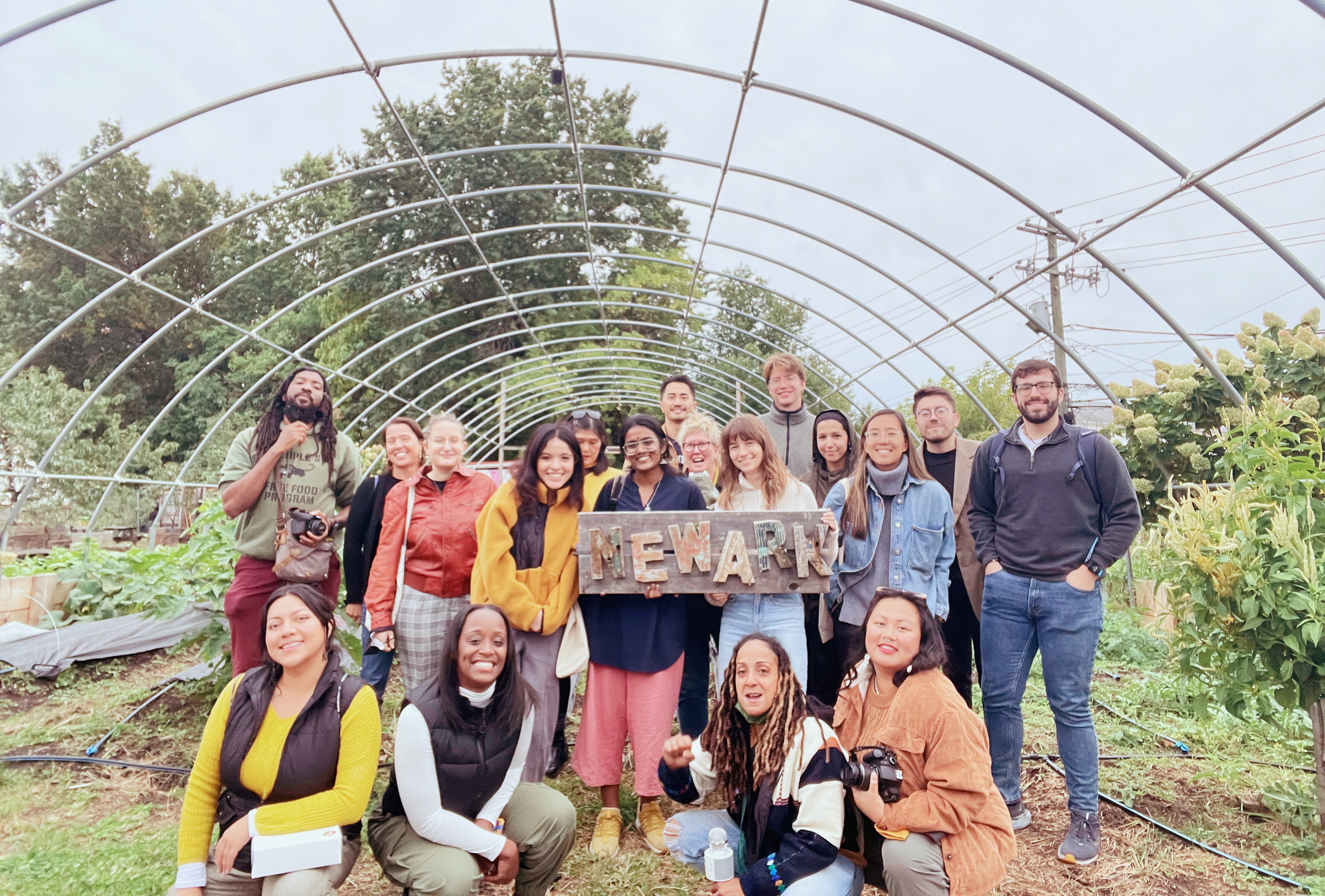 There are a number of people in a garden holding a sign that says "Newark"