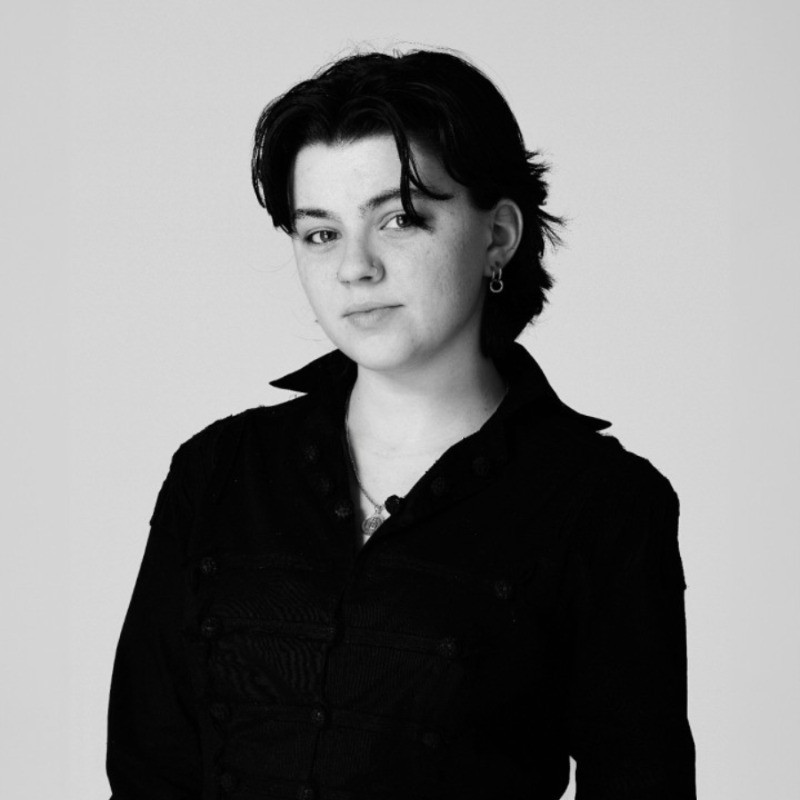 black and white photo of person with short hair in a black shirt. 